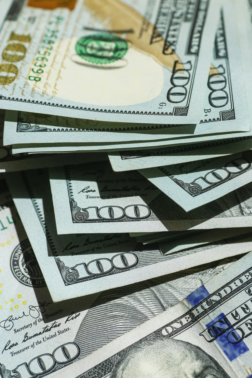 A stack of one hundred dollar bills fanned out in sunlight