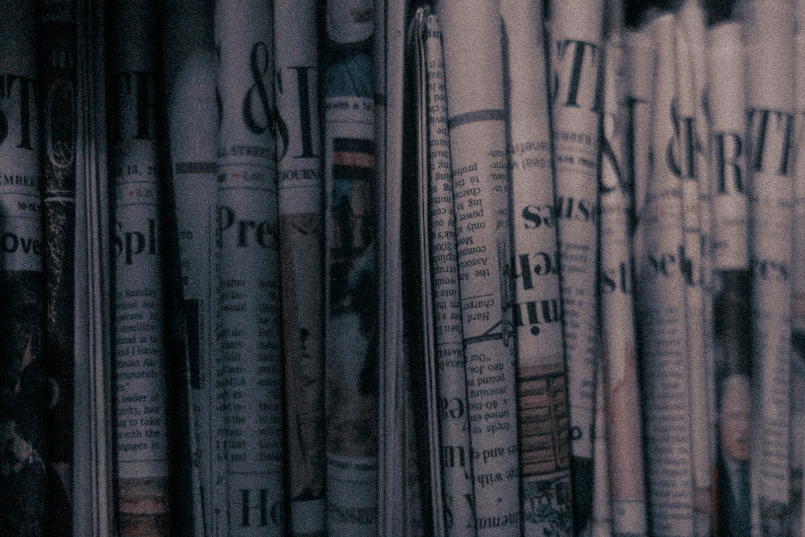 A row of folded newspapers lined up on a rack